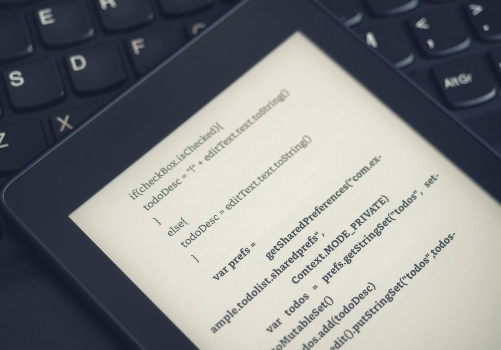 High view of a ebook reader with programing lessons on a laptop keyboard in a coding school