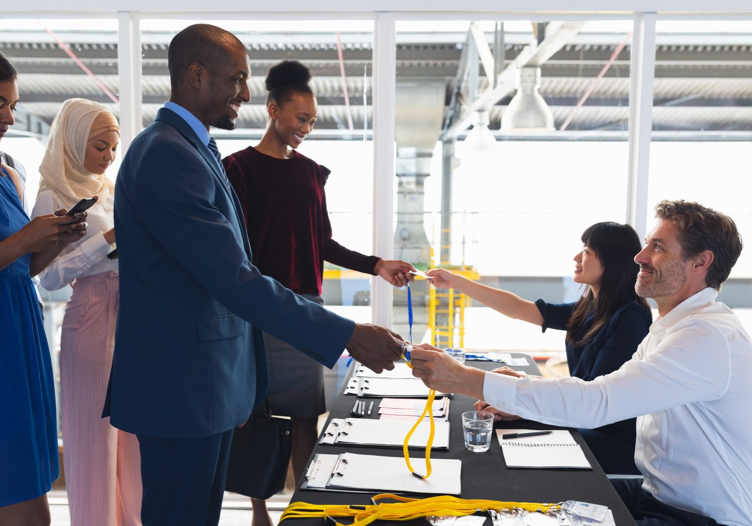 Side view of diverse Business people checking in at conference registration table. International diverse corporate business partnership concept